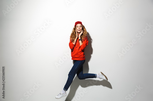 Fototapeta Naklejka Na Ścianę i Meble -  Full length portrait of an excited girl wearing hoodie jumping