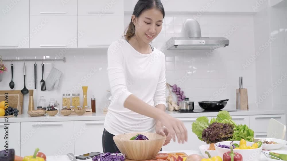 Young Asian woman making salad healthy food in the kitchen, beautiful female in casual use organic vegetables lots of nutrition preparing salad for fit body at home. Healthy food concept. Young Asian woman making salad healthy food in the kitchen, beautiful female in casual use organic vegetables lots of nutrition preparing salad for fit body at home. Healthy food concept.