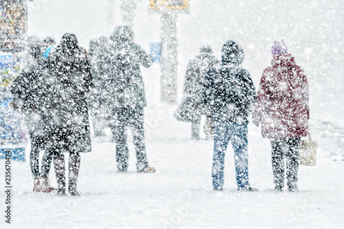 People on bus stop in snowfall © v_sot