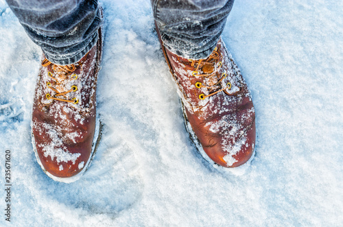 First person view of legs in brown boots in the snow. Snow on boots while walking in winter photo