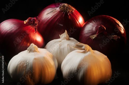 Close up of three red onions and three heads of garlic on a black background photo