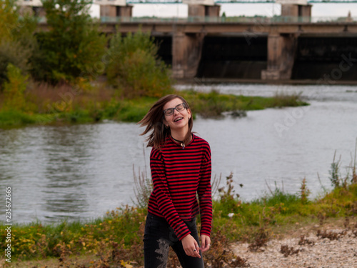 Portrait of a teenage girl gesturing and smiling on the shore of a river