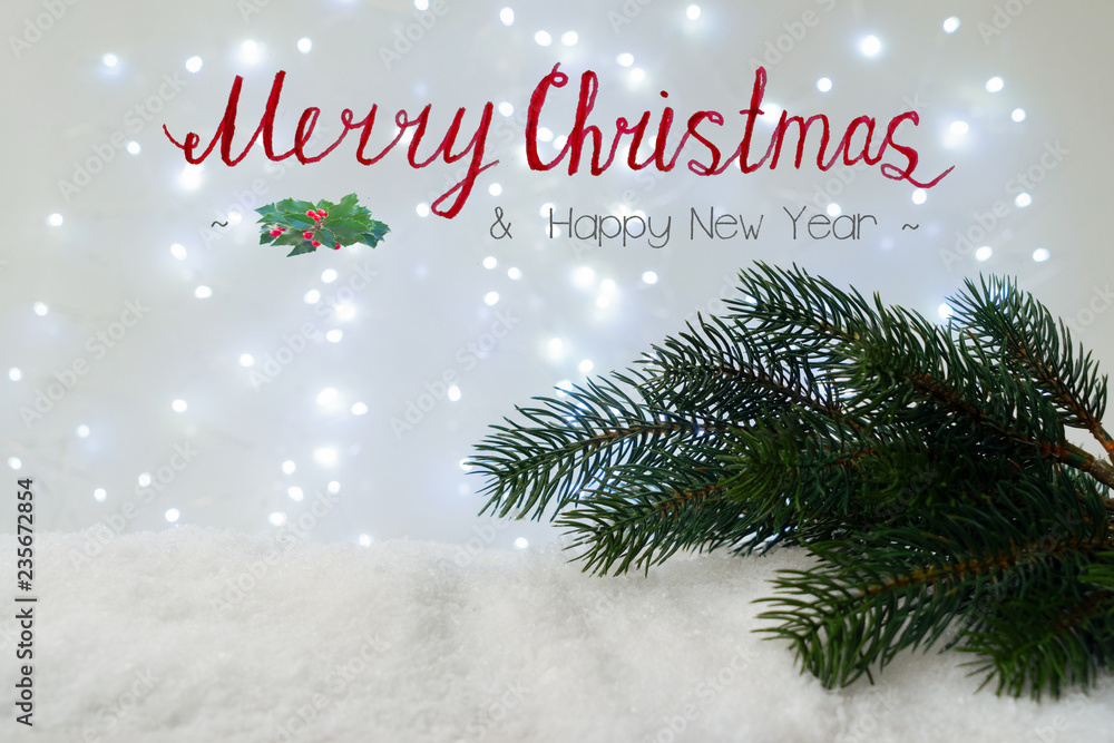 Evergreen fir tree in snow with glowing lights in background with Merry Christmas and Happy New Year greetings Evergreen fir tree in snow with glowing lights in background with Merry Christmas and Happy New Year greetings