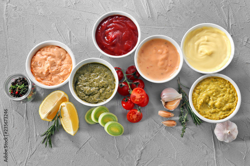 Different tasty sauces in bowls on grey background