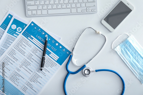 Laboratory test request form with stethoscope and devices on white table. Health care concept