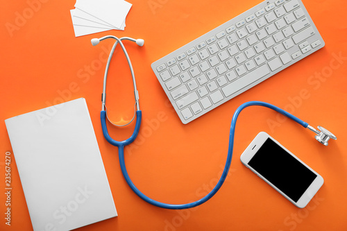 Stethoscope with mobile phone, computer keyboard and notebook on color background. Health care concept