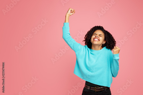 Photo of excited screaming african american young woman standing over pink background. photo