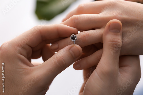 Young man putting engagement ring on fiancee's finger, closeup © Pixel-Shot