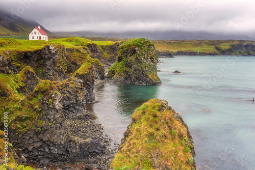 Dramatic icelandic landscape, lonely house on the volcanic cliffs seacoast, Arnarstapi, Snaefellsnes peninsula, Iceland photo