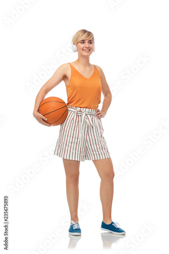 sport, leisure and people concept - smiling teenage girl in headphones with basketball over white background