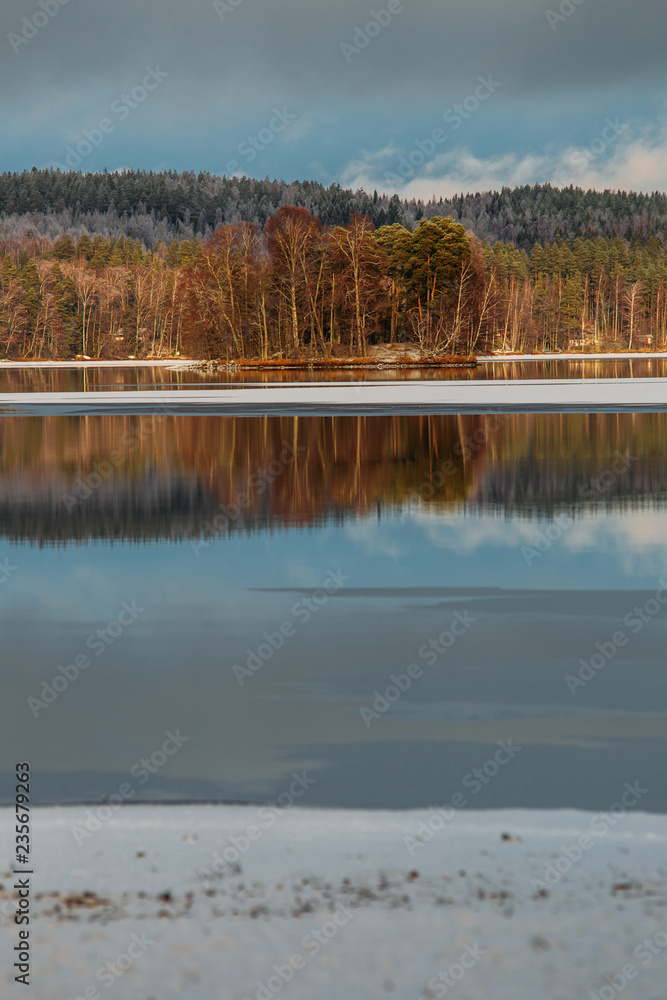 Incredible reflections in the lake with beautiful sunset light. The first frosts in Scandinavia, Finland