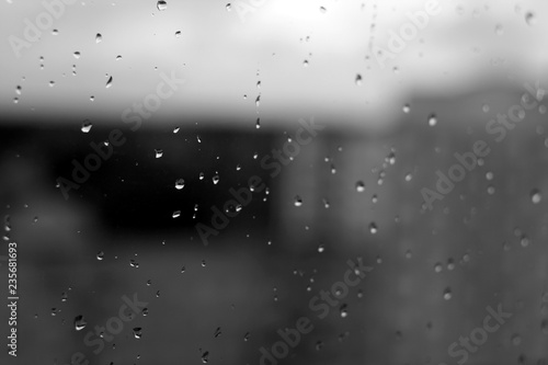 Rain drops on window with blured background in black and white.