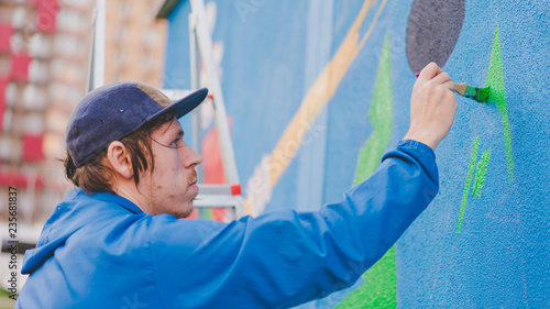 Guy draws paint on the wall on the street