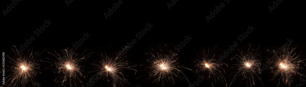 A burning sparkler on a black background with copy space for you design, panorama, new year concept. A burning sparkler on a black background with copy space for you design, panorama, new year concept.