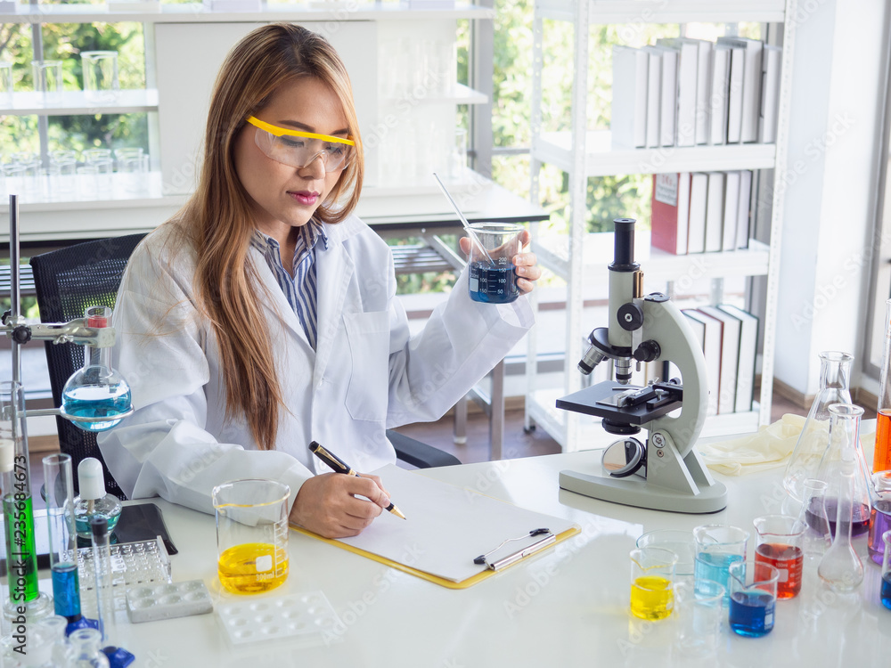 Asia scientific researcher holding a test tube of clear solution in a lab Asia scientific researcher holding a test tube of clear solution in a lab
