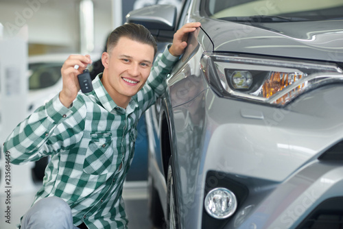 Happy smiling driver buying grey vehicle and showing key. © serhiibobyk