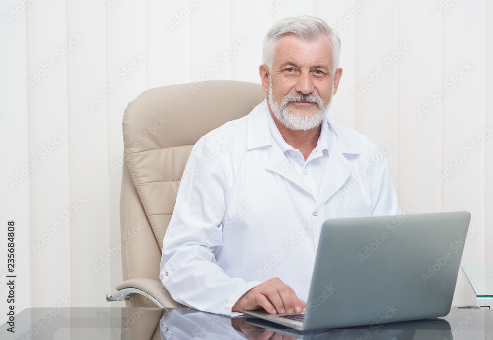 Intelligent senior doctor working on laptop in office. Intelligent senior doctor working on laptop in office.