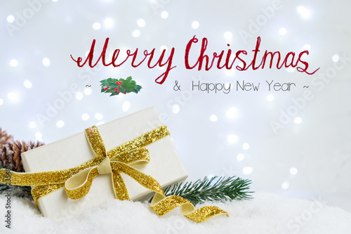 White christmas. gift box with fir tree and decorations in snow, bokeh lights in background with Merry Christmas and Happy New Year greetings photo