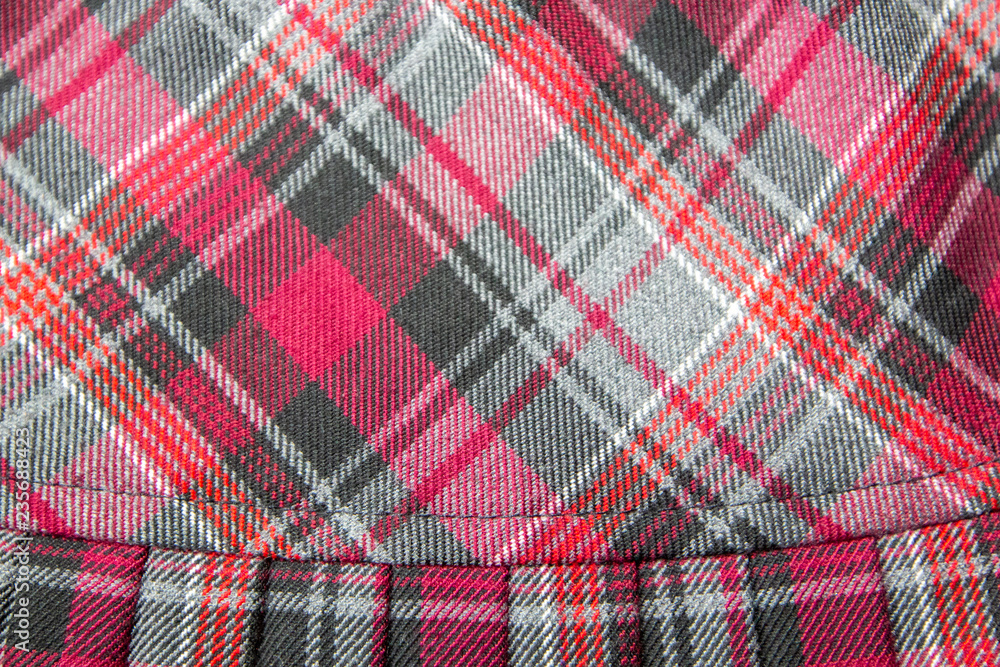 Detail of new fashion plaid pleated skirt: red, maroon, gray tartan school uniform fabric cotton/woolen material, blurred focus Detail of new fashion plaid pleated skirt: red, maroon, gray tartan school uniform fabric cotton/woolen material, blurred focus