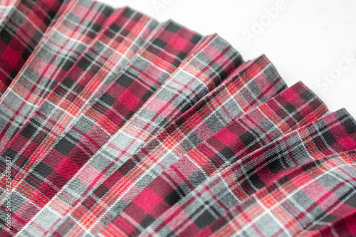 Detail of new fashion plaid pleated skirt: red, maroon, gray tartan school uniform fabric cotton/woolen material, blurred focus