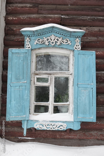 Window with carved frame of old wooden house in Solyanoy Lane, Tomsk city (Russia). Russian folk style in architecture. View, sight, architectural landmark, monument of Tomsk town. Snow winter photo