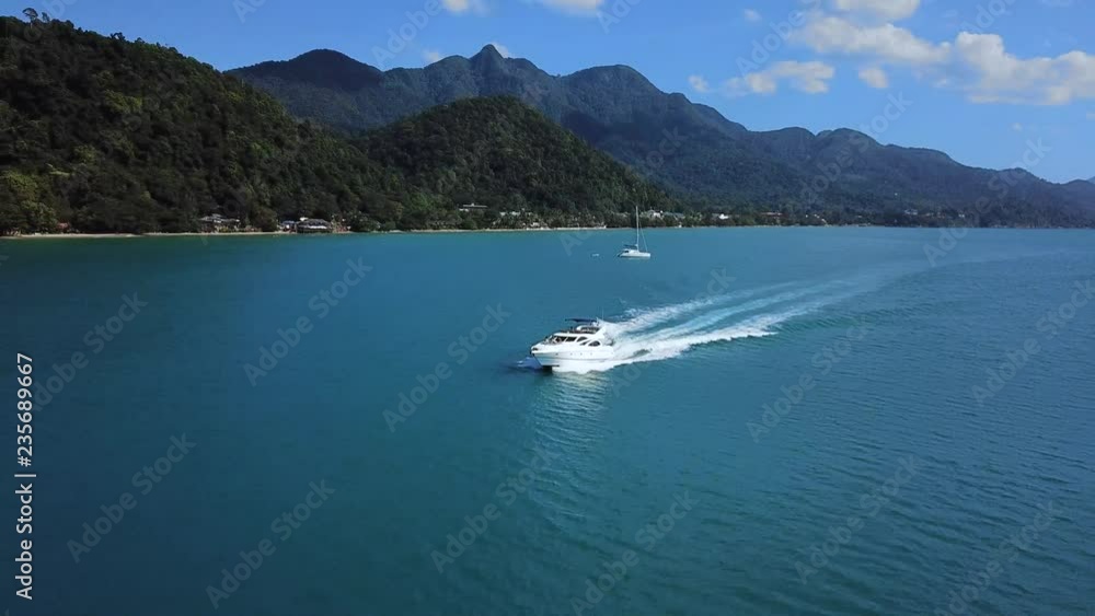 Yacht motorboat cruising in blue tropical sea water near island coastline, drone aerial footage, beautiful landscape, vacation holiday leisure Yacht motorboat cruising in blue tropical sea water near island coastline, drone aerial footage, beautiful landscape, vacation holiday leisure