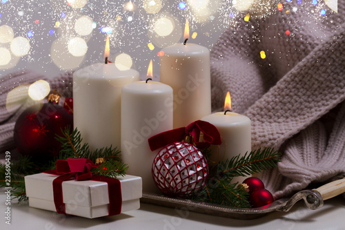 White burning advent candles with christmas decorationswith bokeh lights