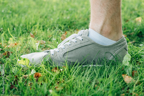 Male feet in gray gumshoes on grass