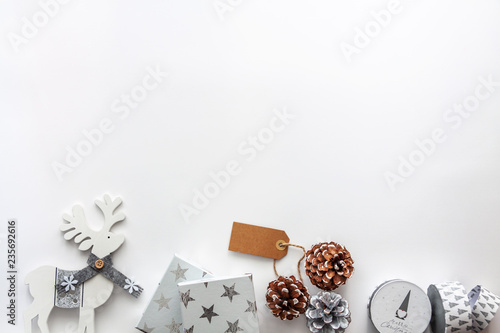 White gifts, reindeer and pine cones on the white copy space background. Empty space for text, flat lay, above view