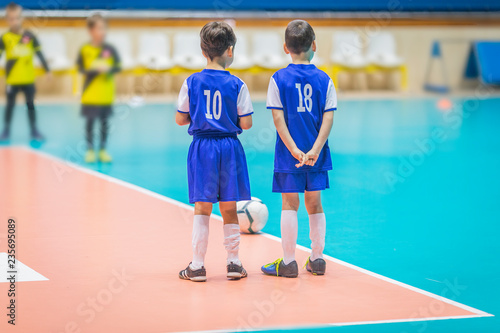 kids in blue teams train and play football in the hall. girls and boys play together soccer.
