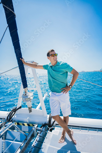 Sexy successful man on sailboat, relaxation in luxury sea cruise, summertime leisure time on water transport, freedom and enjoyment concept.