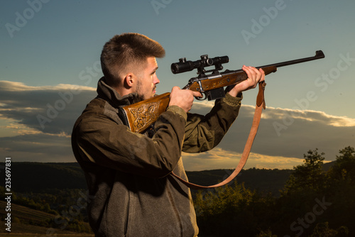 Hunting Gear - Hunting Supplies and Equipment. Hunter with shotgun gun on hunt. Hunter with Powerful Rifle with Scope Spotting Animals.