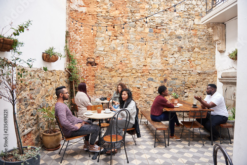 Foto Diverse people talking over coffee in a trendy cafe courtyard