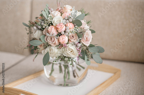 Wedding bouquet in shades of dusty rose, white, green, beige, pink and purple. Beautiful and delicate bridal bouquet in the glass vase.