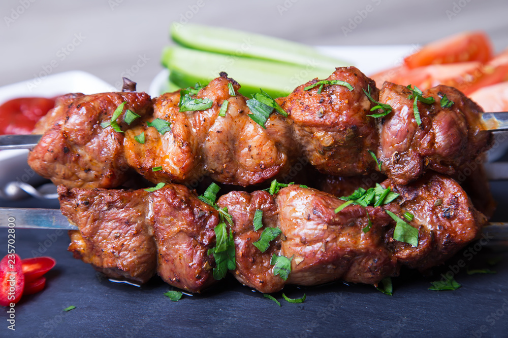 Shashlik (shish kebab) of meat (pork) on skewers with vegetables and ketchup. Close-up, selective focus.