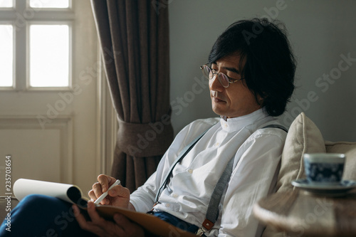 Businessman wearing eyeglasses and suspenders writing in notebook photo
