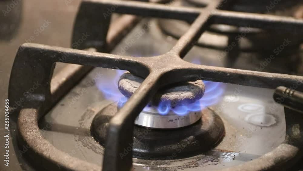 Turning on the kitchen cooktop gas cooker by auto lighter close up on the flame. Natural gas burning inflammation in stove gas burner Turning on the kitchen cooktop gas cooker by auto lighter close up on the flame. Natural gas burning inflammation in stove gas burner