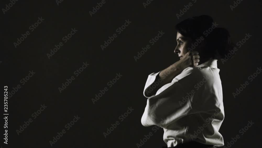girl practicing karate, wearing kimono, on dark background. slow motion recorded at 120fps