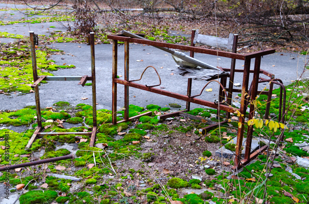 Fototapeta premium Rusty metal frame of table and chair in schoolyard in dead abandoned ghost town of Pripyat in Chernobyl alienation zone, Ukraine