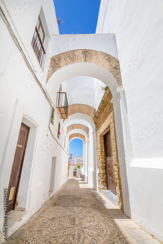 vertical shot of narrow pedestrian famous street with archs, in typical white houses Andalusian village named Vejer de la Frontera (Cadiz, Andalusia, Spain, Europe) © Q