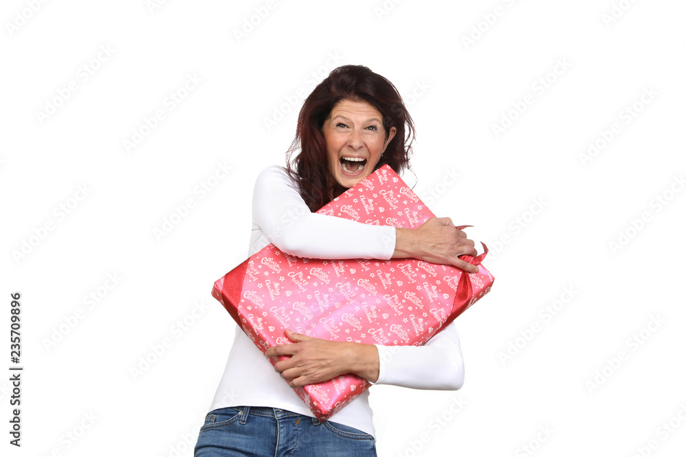 Ältere Frau ist begeistert und hält ein Weihnachtsgeschenk umarmt Ältere Frau ist begeistert und hält ein Weihnachtsgeschenk umarmt
