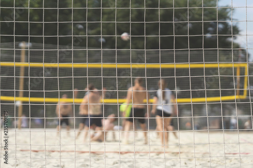 Group of young friends playing game volleyball on beach on summer day, selectiv focus. Blurred background, healthy lifestyle