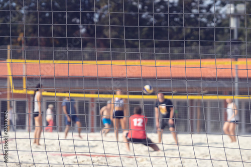 Group of young friends playing game volleyball on beach on summer day, selectiv focus. Outdoor sport