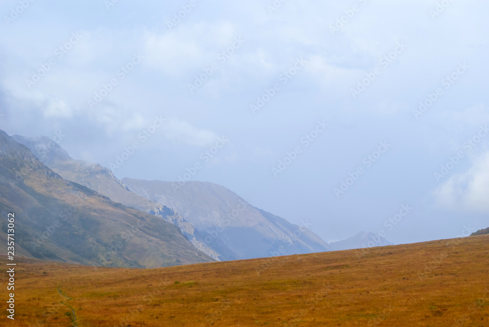steppe plateau, alpine meadow in autumn with a foggy ridge in the distance