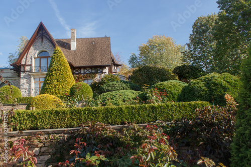 Cottage garden with vines, trees and trimmed bushes.