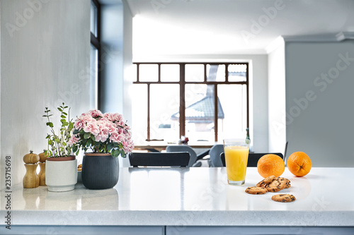 Appetizing sweet orange juice and one drinking glasses standing on a white table in the kitchen for a breakfast.