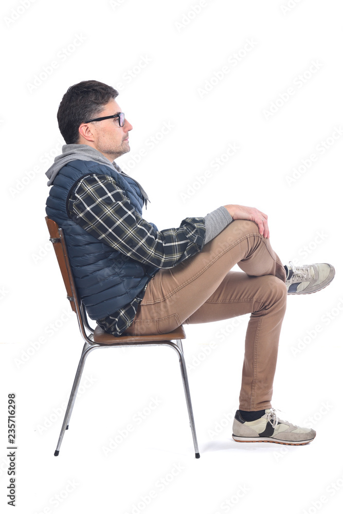portrait of a man sitting on a chair legs and arms crossed looking to the side