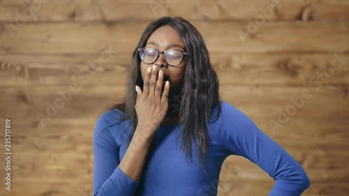 Black beautiful girl yawns covering her mouth with her hand photo