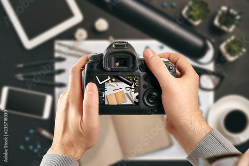 Digital single-lens reflex camera in hands. Man photographer makes photos. Male hands hold the camera close-up