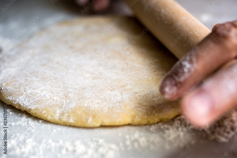 Close up of man's hands rolling dough with rolling pin Close up of man's hands rolling dough with rolling pin